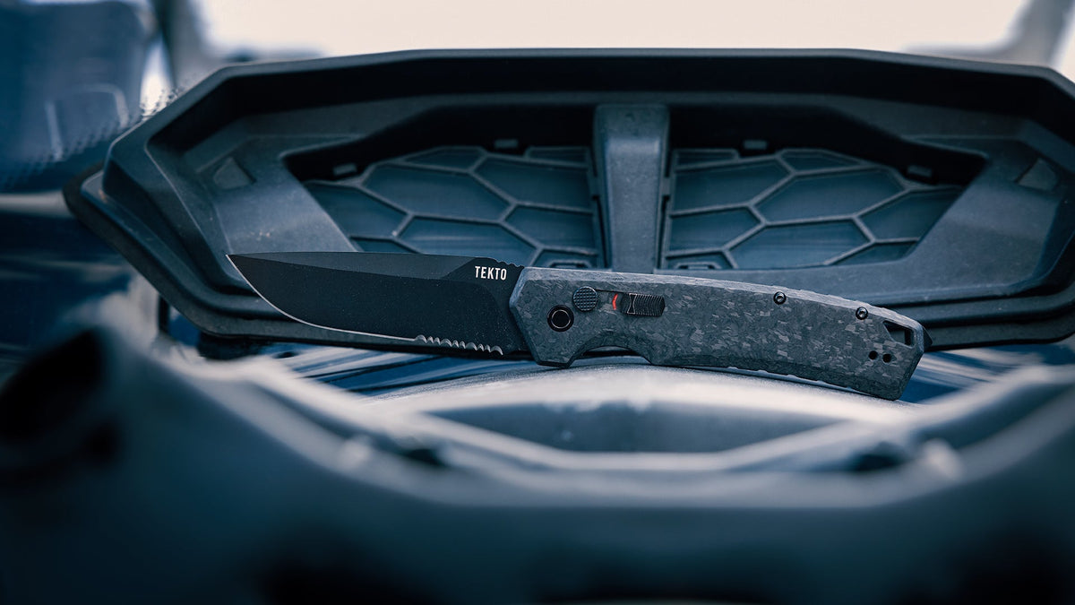 A TEKTO folding knife resting on a vehicle's center console