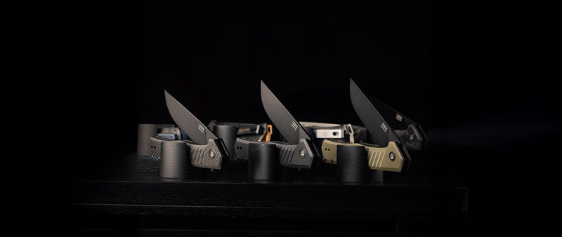 A lineup of TEKTO folding knives on a dark background