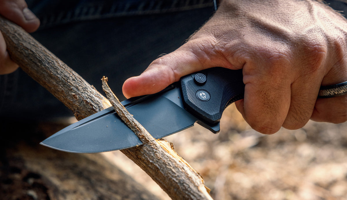 Hand carving a branch with a black TEKTO folding knife